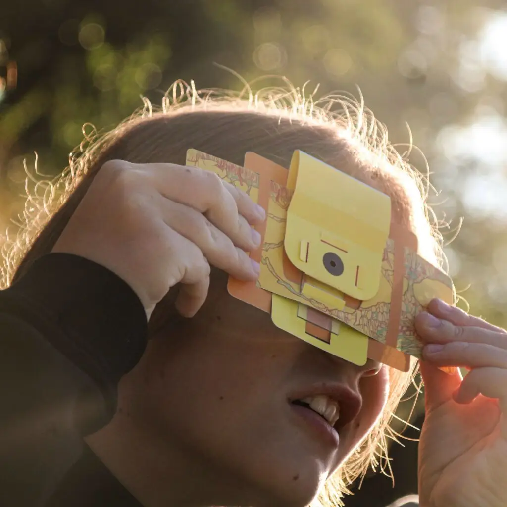 Une jeune fille observe quelque chose avec un foldscope.