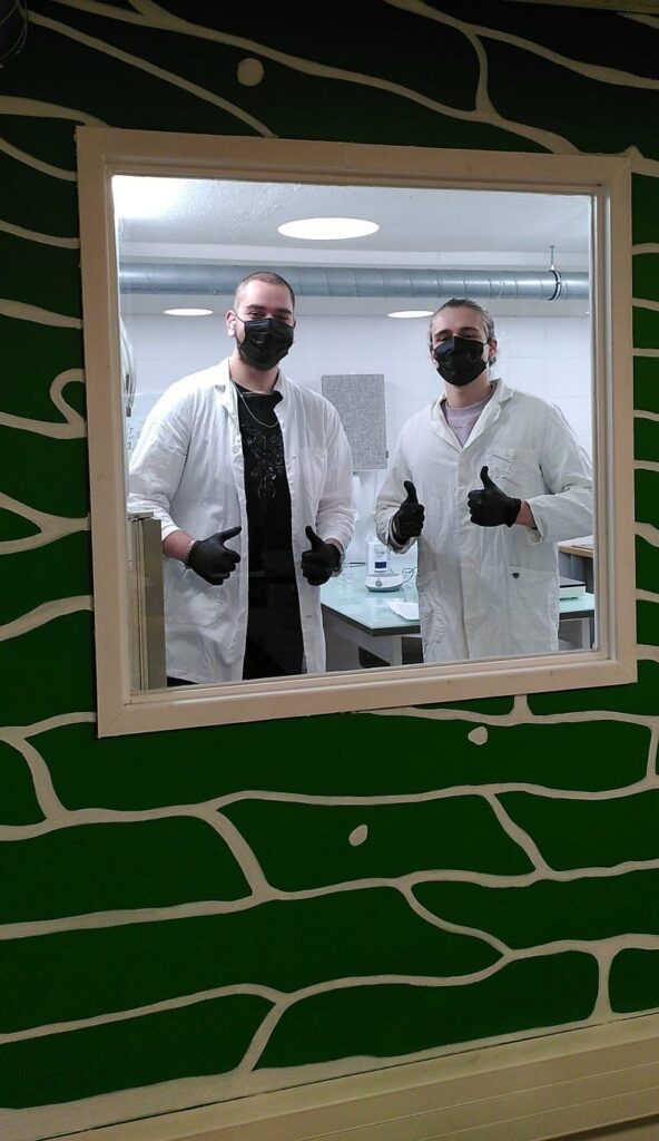 Deux membres de l’équipe H2wOw en blouse et masque au laboratoire, pouce levé